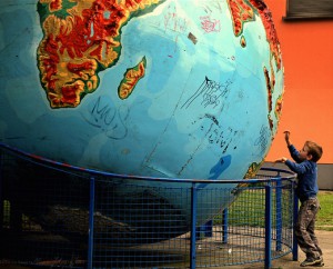 Boy reaches up to touch battered statue of earth