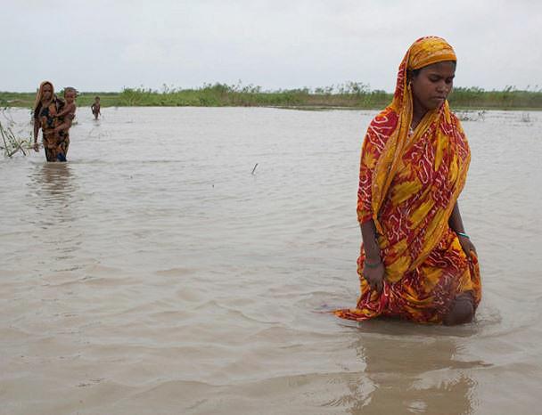  Climate Displacement in Bangladesh: The Jamuna River has swollen from heavier than usual monsoon rainfall causing severe flooding on the islands. Women on Dakkin Patil Bariare are forced to wade across waterlogged land. August 2011 (Photo by Stuart Matthews) Creative Commons license via Flickr
