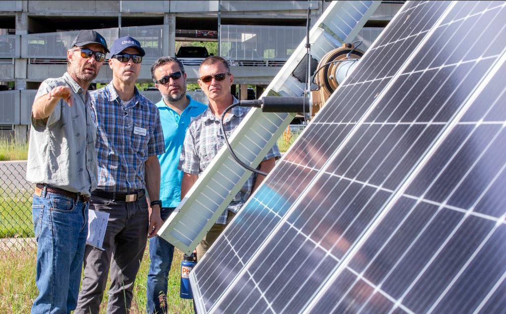 U.S. National Renewable Energy Lab (NREL) research technician Otto Van Geet (left) gives a tour of the Photovoltaic Central Array Testing Site to participants in NREL's Executive Energy Leadership Academy, June 20, 2019 (Photo by Werner Slocum / NREL)