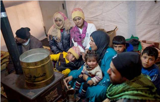 Members of a Syrian refugee family huddle around a stove inside their shelter in Lebanon’s Bekaa Valley. 2013 (Photo by A. McConnell courtesy UNHCR) Posted for media use