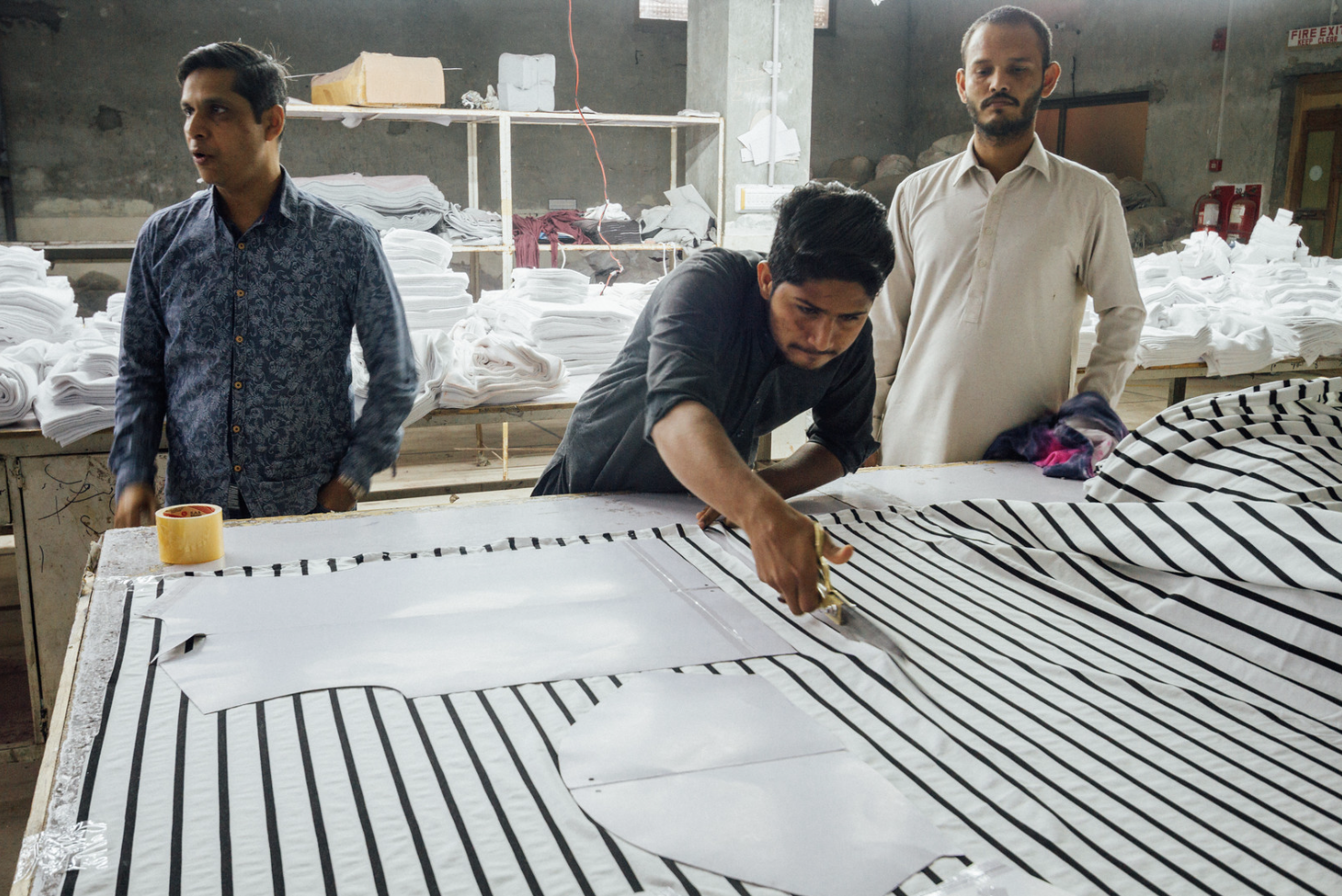 Garment workers cut cloth to pattern sizes at a clothing factory in Faisalabad, Punjab, Pakistan, March 3, 2020 (Photo by Adam Cohn) Creative Commons license via Flickr 