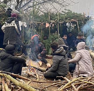 Refugees huddle around a fire in sub-zero temperatures near the border of Belarus and the European Union. (Photo courtesy UN International Organization for Migration via Twitter) Posted for media use