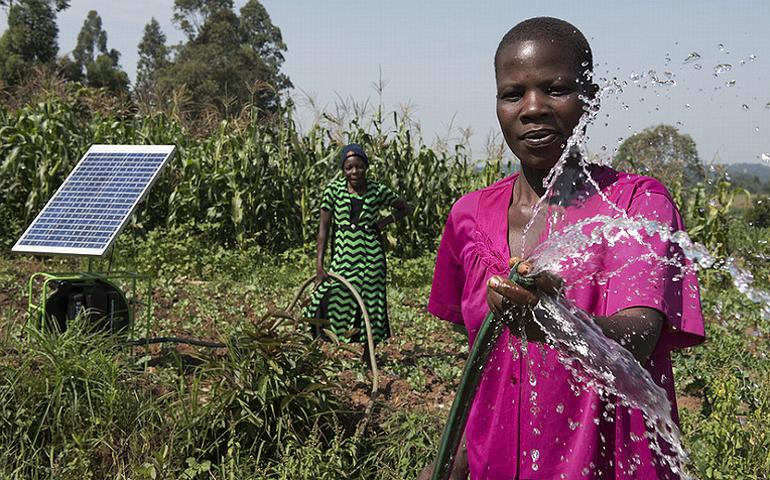 Jenepher Wanjala poses with the Sunflower solar irrigation pump outside of Kitale, Kenya, under the watchful eye of the farm's owner, Carol Sikuku. March 18, 2018 (Photo by Jeffery M. Walcott / International Water Management Institute). Creative Commons license via Flickr.